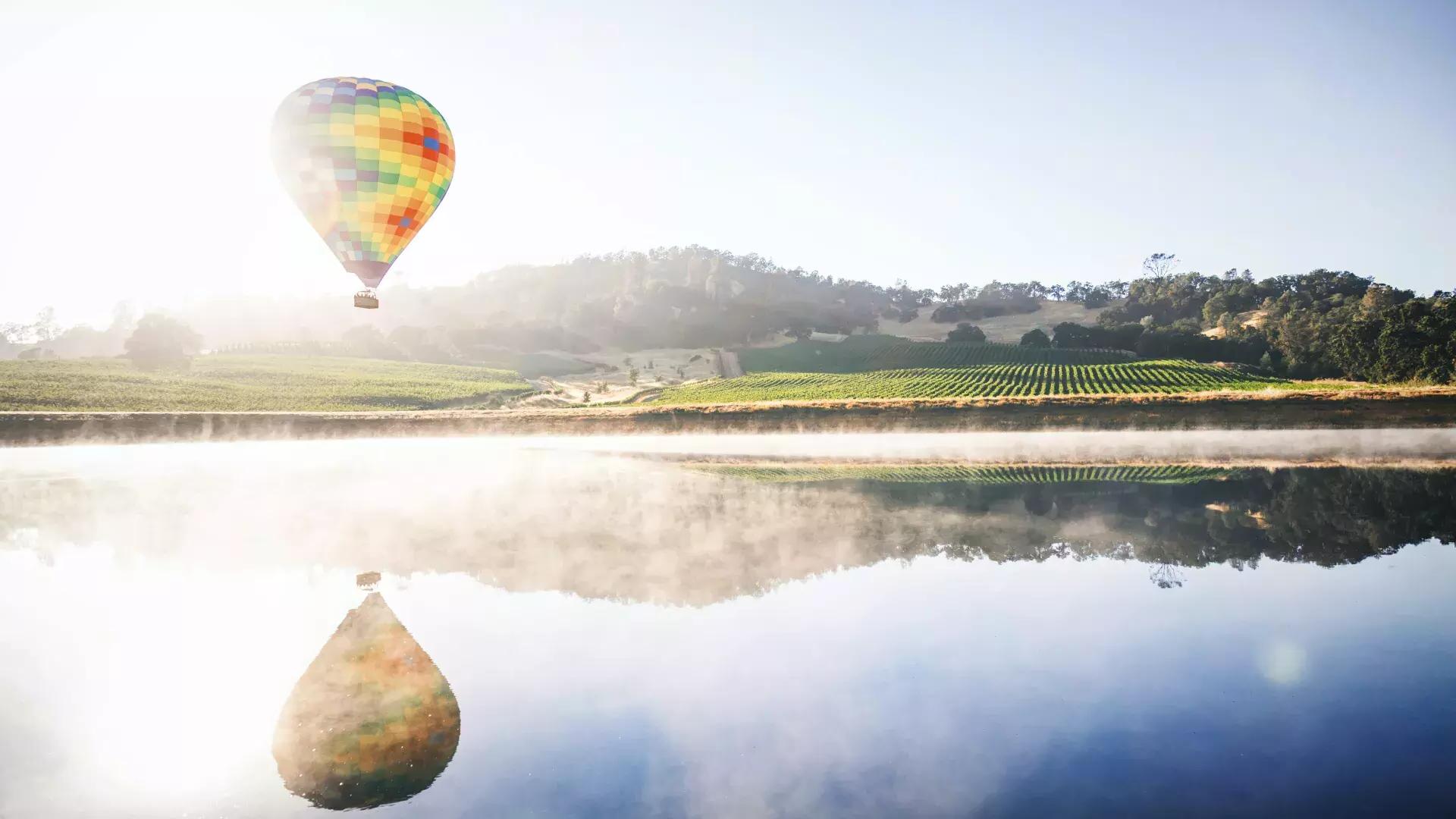 Globo aerostático flotando sobre un viñedo.